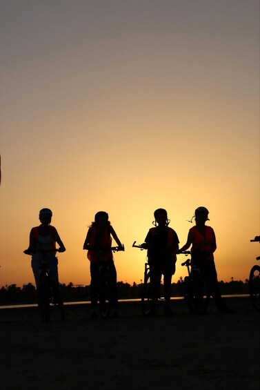Four people on bicycles silhouetted against a sunset. 3
