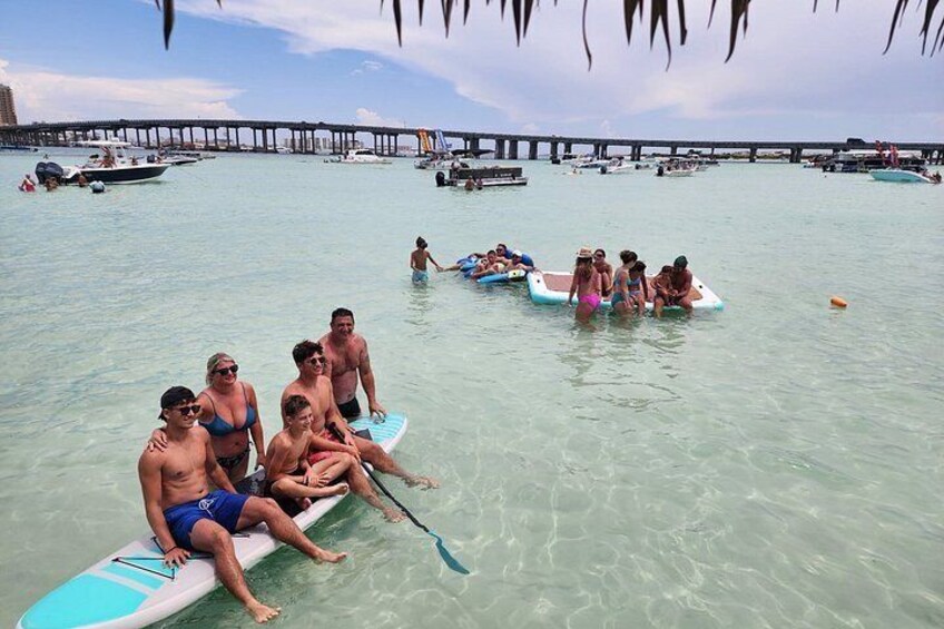 Personas en tablas de remo en un puerto deportivo con barcos y un muelle al fondo. 2