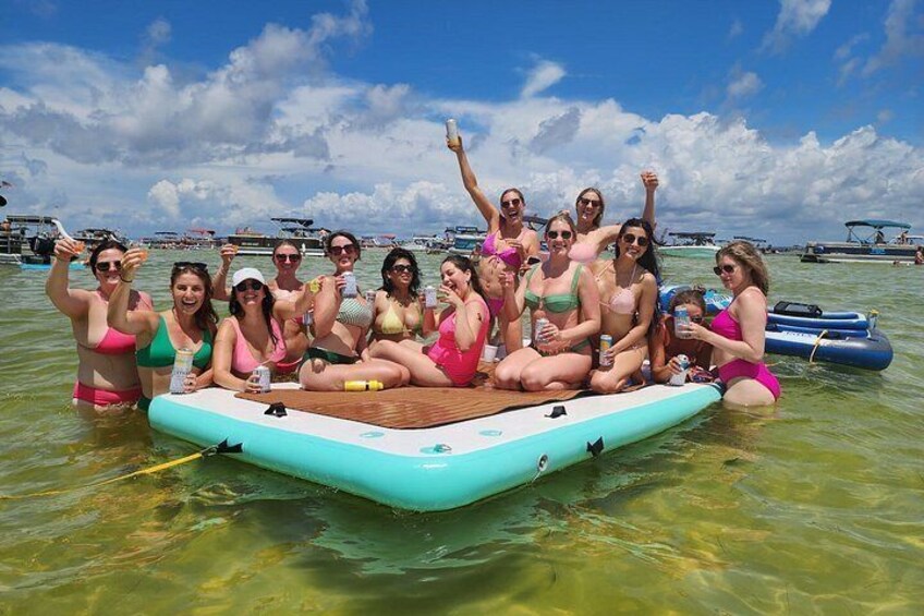 Un grupo de personas en una plataforma flotante en aguas transparentes, con embarcaciones al fondo. 5