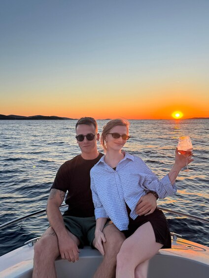 Two people on a boat at sunset with the sun visible on the horizon. 4