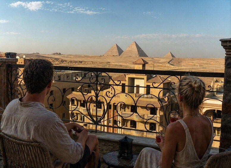 Two people seated on a balcony overlooking the pyramids. 2
