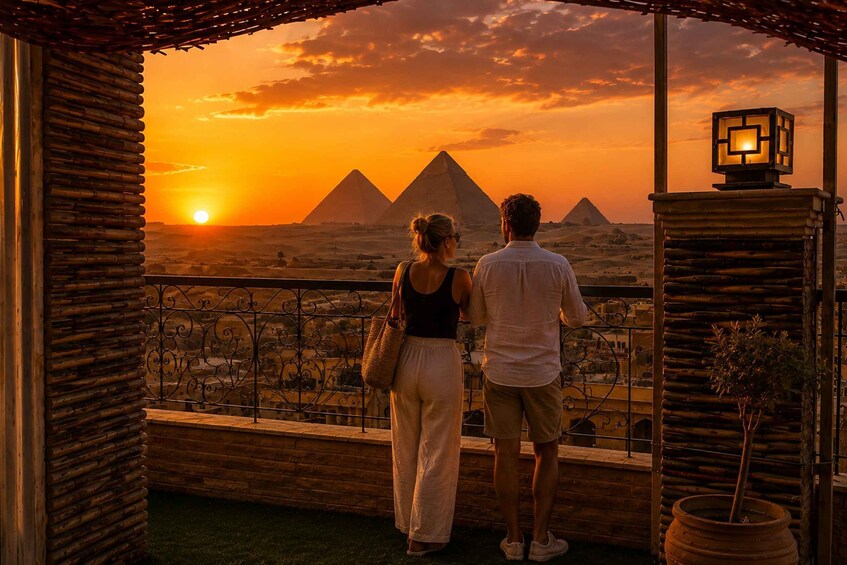 A couple overlooking a sunset with pyramids in the background. 1