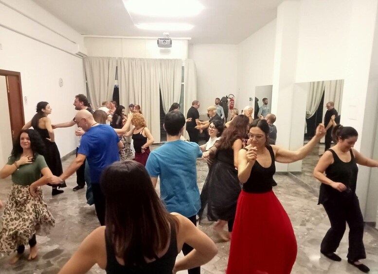 A group of people dancing in a room with white walls and a tiled floor. 2