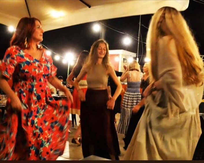 People dancing at an outdoor event under a tent. 4