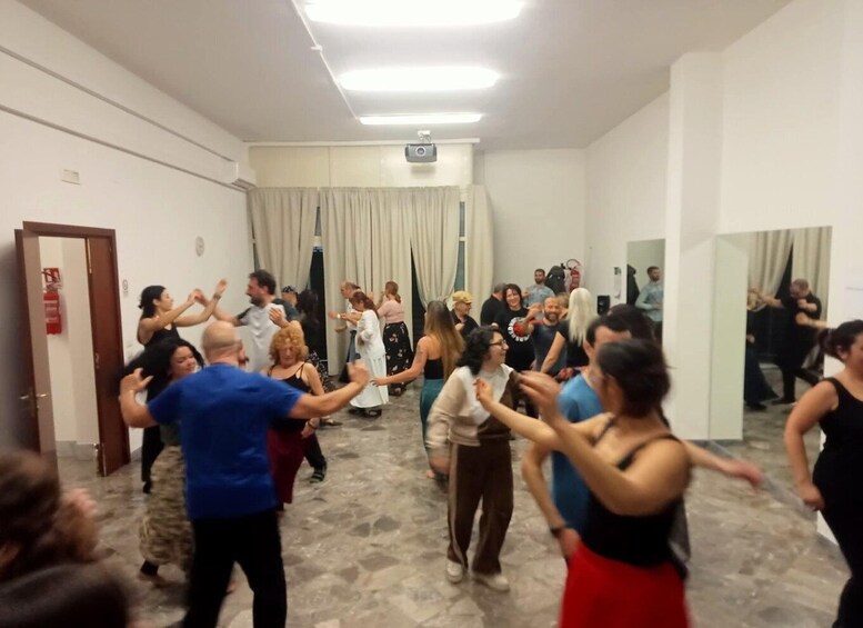 A group of people dancing in a room with a projector on the wall. 3
