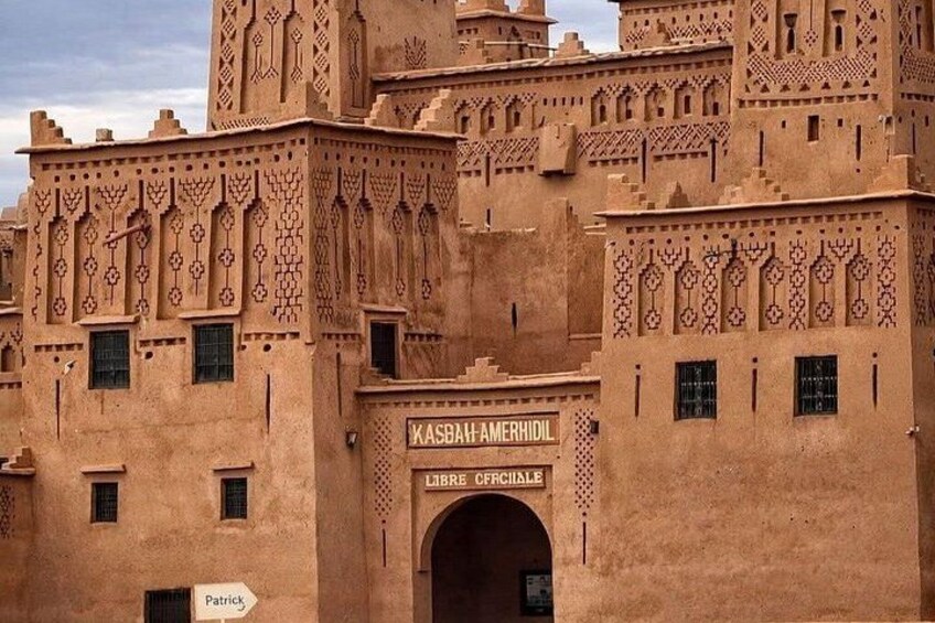 A traditional kasbah with intricate geometric patterns and a sign reading 'KASBAH AMERHIDL LIBRE OFFICIALE'. 2