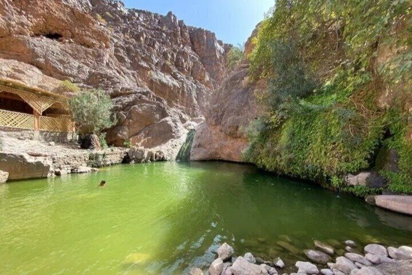 A green river in a canyon with a waterfall, rocks, and a wooden structure. 3