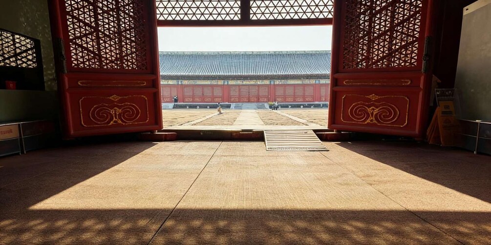 A traditional Korean gate with intricate designs, leading to a courtyard with a tiled roof structure. 5