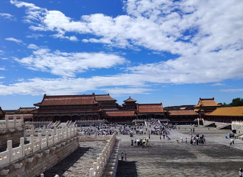 A traditional Chinese architectural complex with multiple buildings, a large open courtyard, and a stone wall with a gate. 4