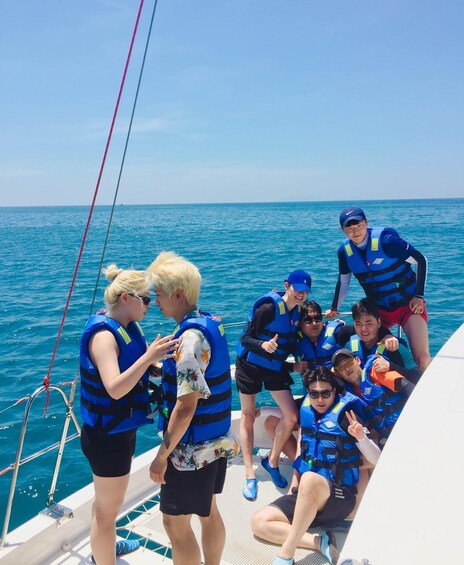 A group of people on a boat wearing life jackets, with the ocean in the background. 4