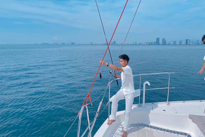 A person on a boat handling ropes, with a city skyline in the background. 5