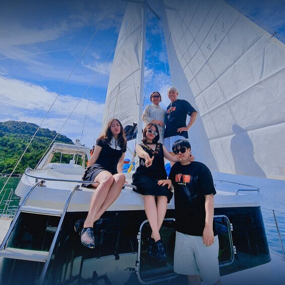 A group of people on a sailboat with a mountainous landscape in the background. 3