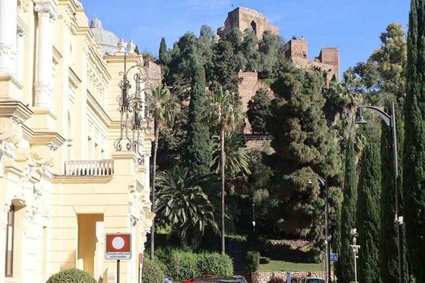 A historic building with ornate architecture, a hilltop fortress, and lush greenery. 2