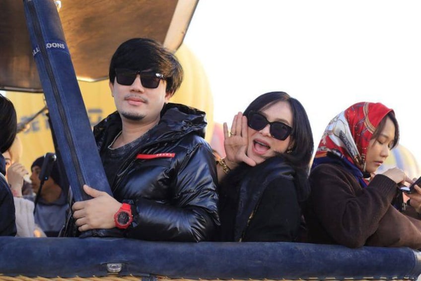 People sitting on a bench, a person holding a blue object, and a person wearing a red watch. 1