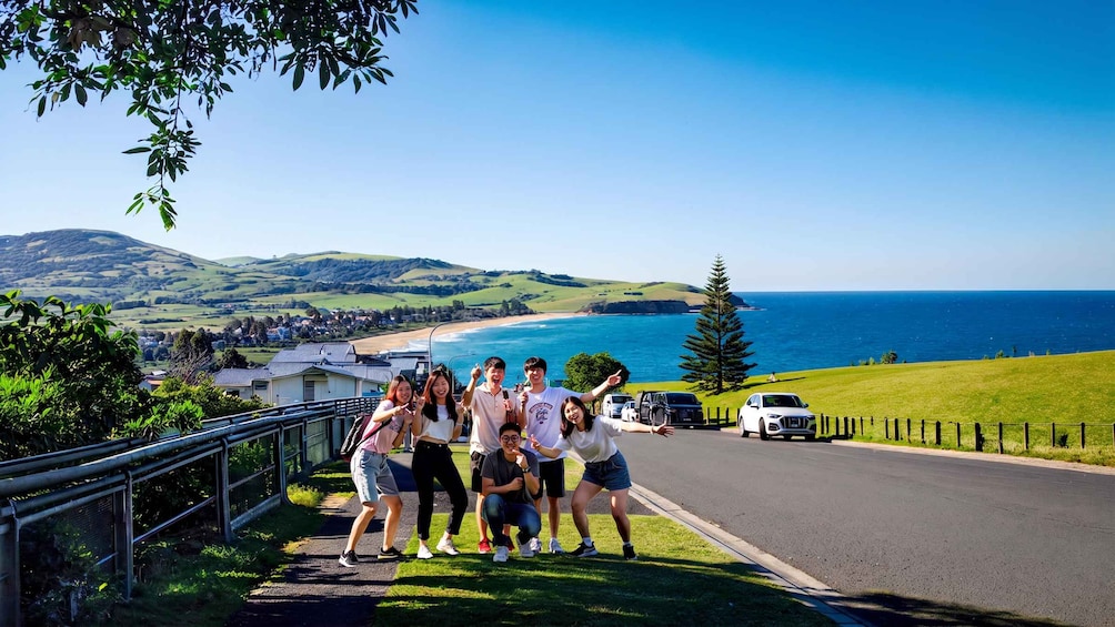 A group of people posing on a road with a coastal landscape in the background. 5