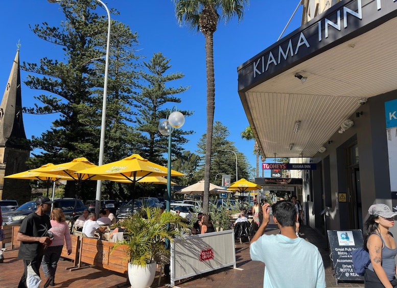 Outdoor seating with yellow umbrellas, a building with a sign reading 'KIAMA INN', and a street lamp. 4