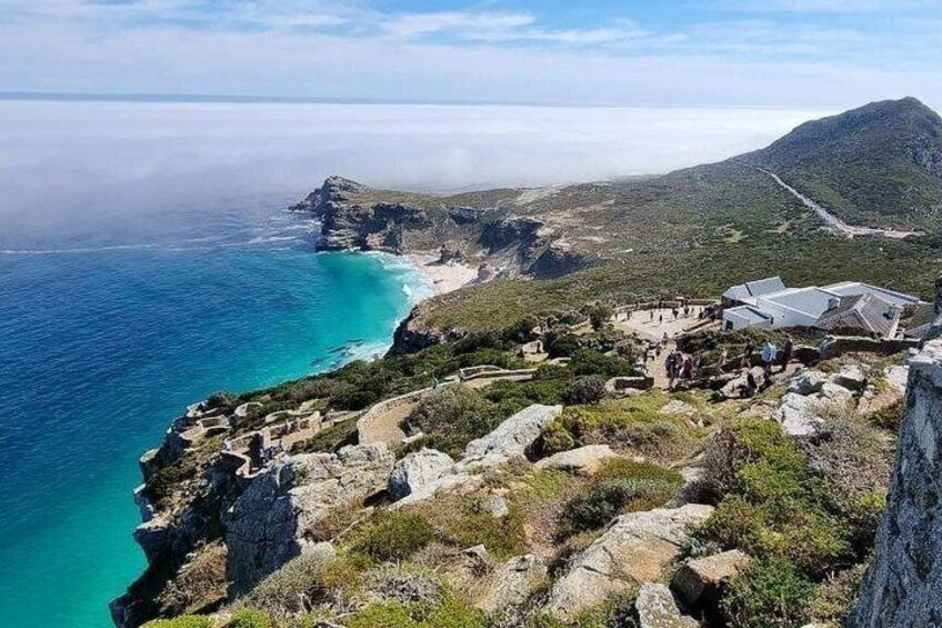 Ett kustlandskap med klippor, en strand och ett berg i bakgrunden. 5
