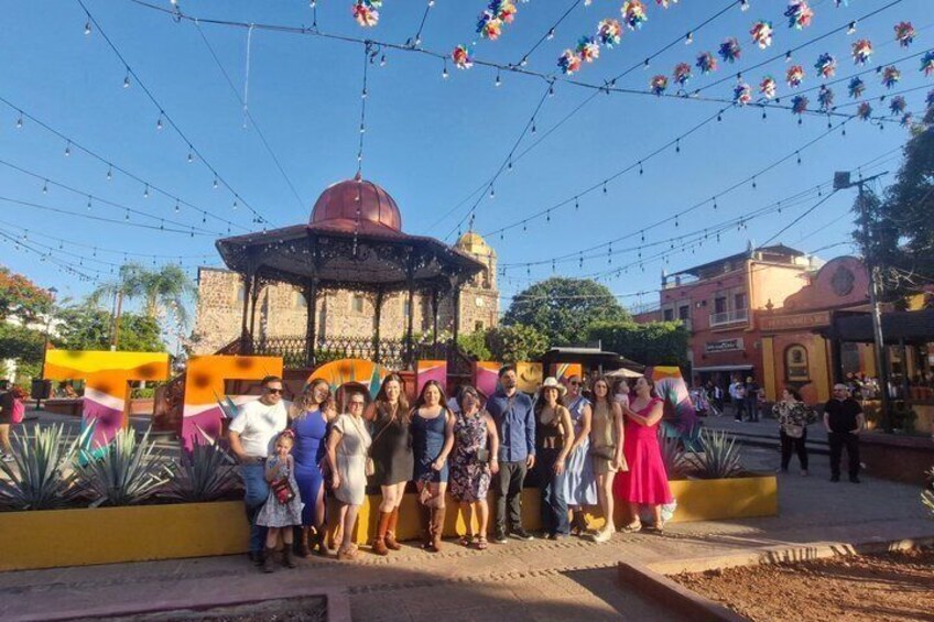 A group of people standing in front of a gazebo with a dome roof, under string lights. 5