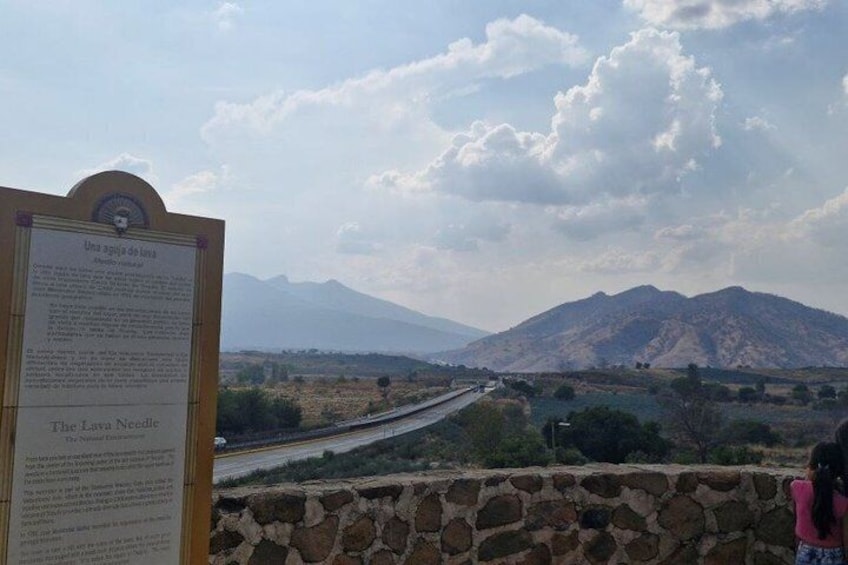 A stone wall, a signboard, and a mountain range in the distance. 3