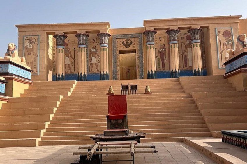 Un'imponente ingresso con scalinate che conducono a un tempio, decorato con geroglifici e statue. 2