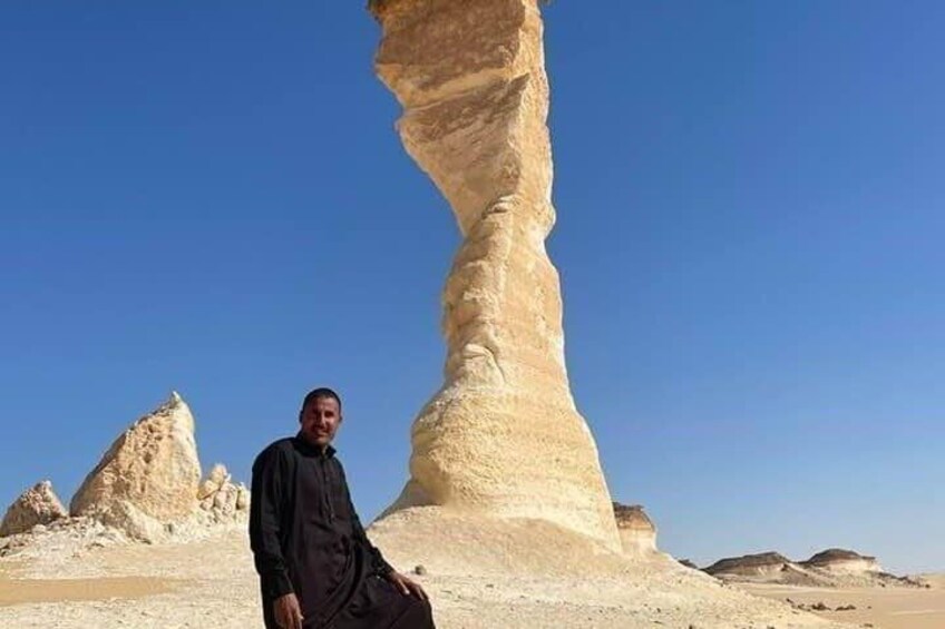 A person standing in front of a large rock formation in a desert landscape. 2