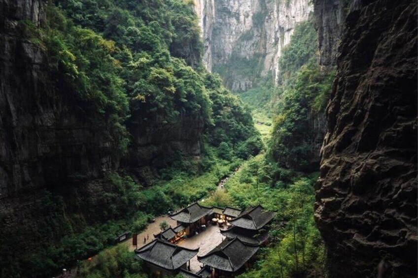 A traditional building nestled in a lush valley with steep cliffs. 1