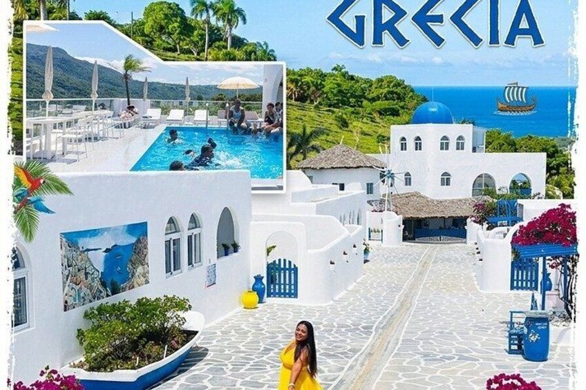 Un edificio blanco con piscina, cielo azul y un barco en el mar. 1