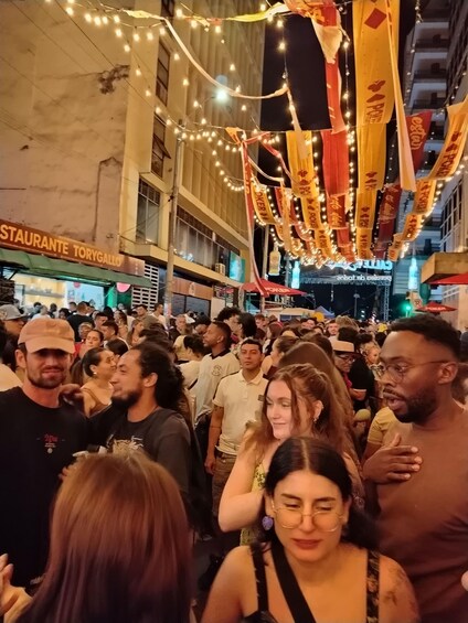 A crowded street with people, a restaurant named 'STAURANTE TORYGALLO,' and decorative lights. 5