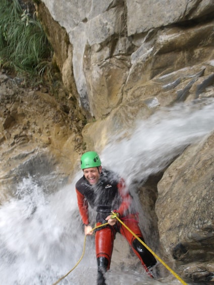 A person rappelling down a rocky cliff with flowing water. 3
