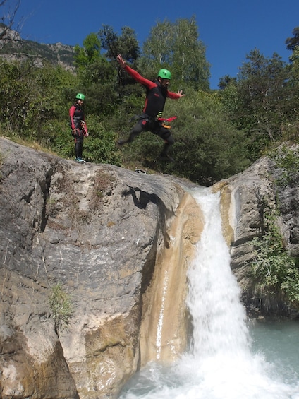 Two people jumping off a rocky cliff into a waterfall. 5