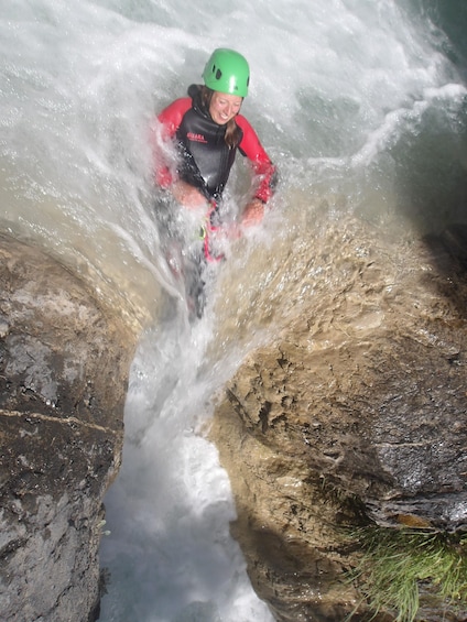A person in a wetsuit and helmet navigating through a turbulent water stream. 4