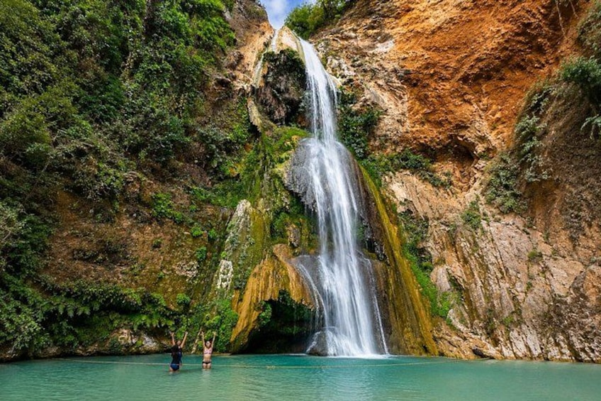 Una cascada se precipita desde un acantilado rocoso hacia una piscina turquesa rodeada de exuberante vegetación. 1