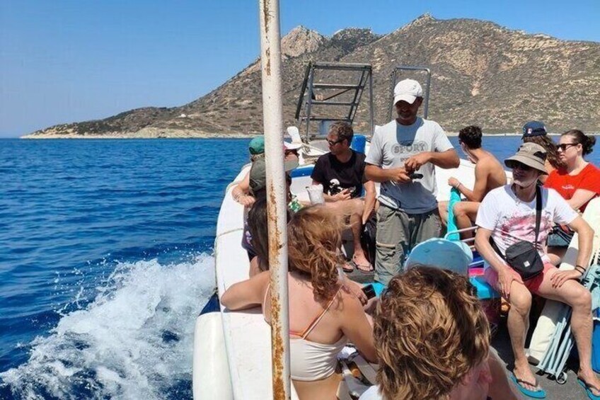 Un groupe de personnes se trouve sur un bateau, avec un paysage montagneux en arrière-plan. 3