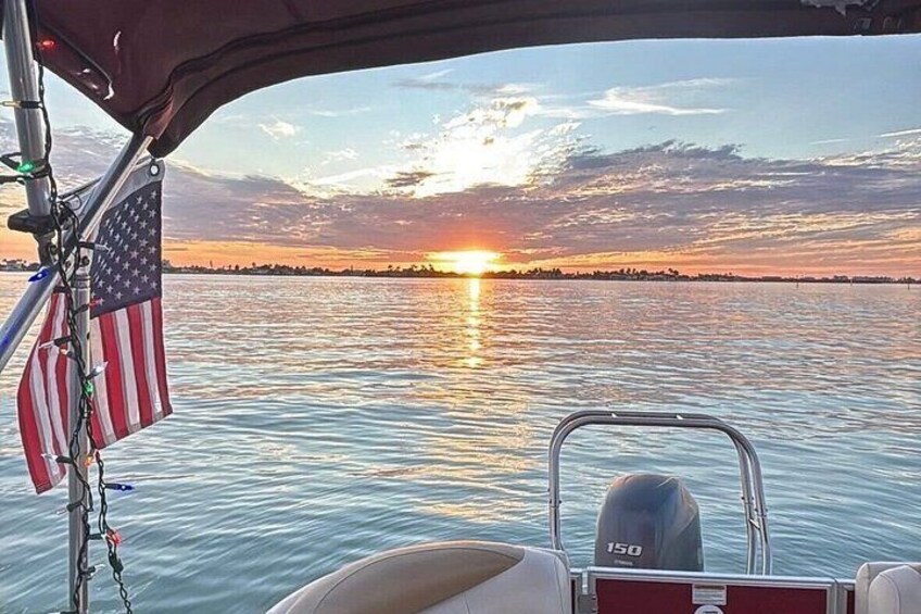 Un atardecer sobre el agua con una bandera estadounidense y el motor de un barco. 1