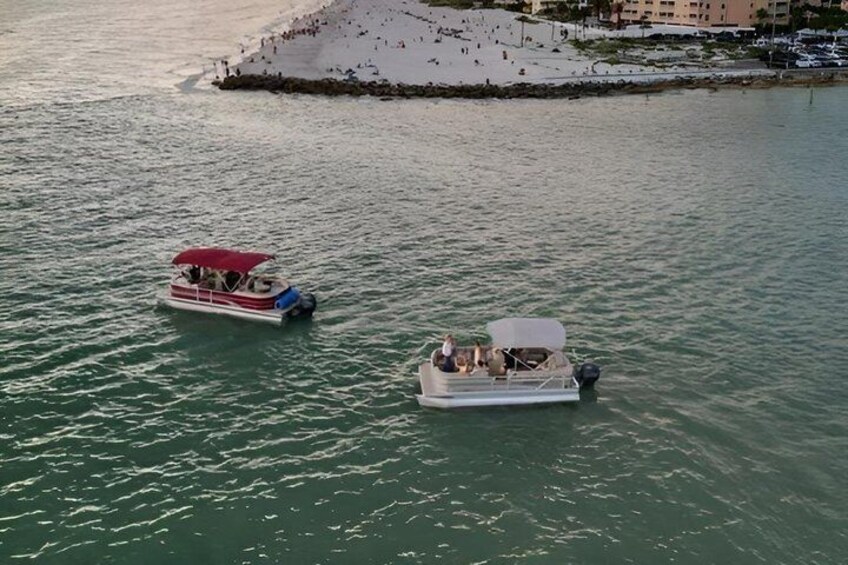Due barche su acque calme, una spiaggia sabbiosa e edifici sullo sfondo. 1