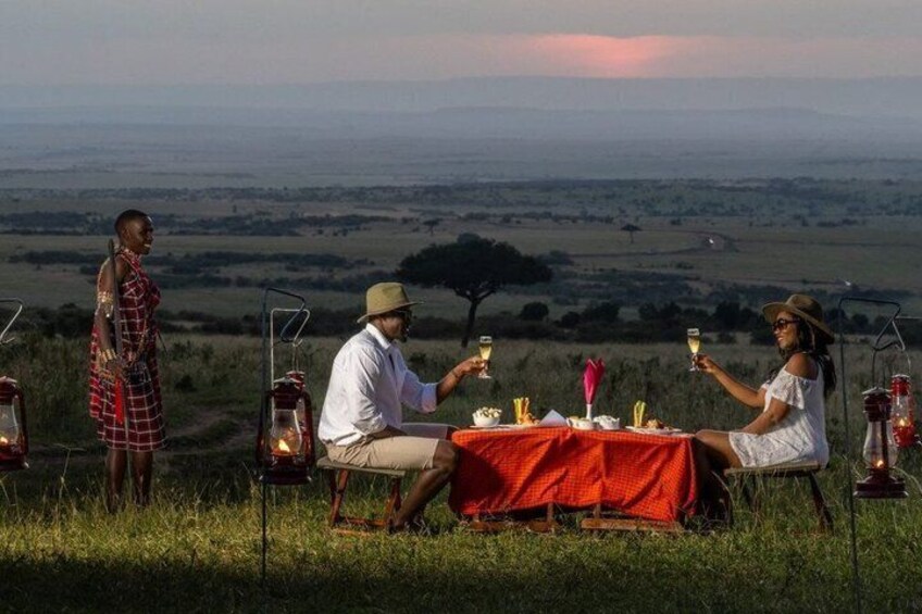 Un groupe de personnes est réuni autour d’une table dressée pour un repas, en plein air, et l’ambiance est illuminée par des lanternes. 2