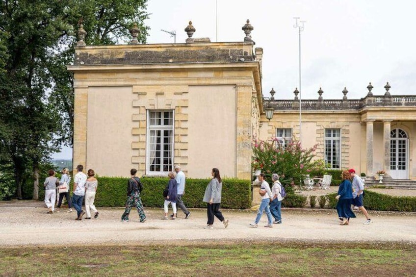 A historic building with classical architecture, a paved walkway, and a garden with trimmed hedges. 2