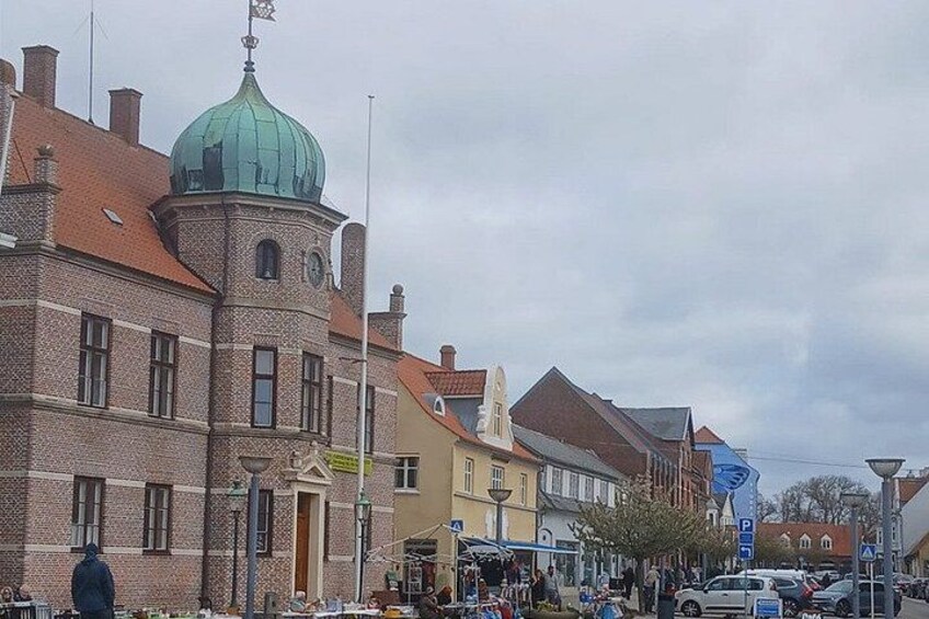 Una calle con edificios históricos, una cúpula verde destacada y una señal de estacionamiento azul. 3