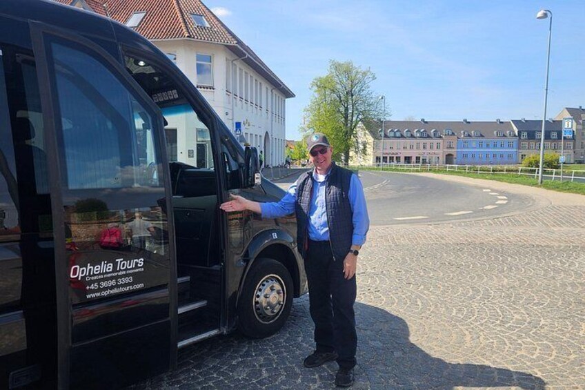 En mand står ved siden af en sort varevogn med teksten 'Ophelia Tours'. 2