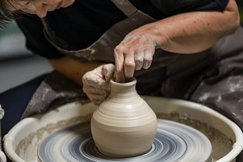 A person shaping a clay pot on a pottery wheel. 4