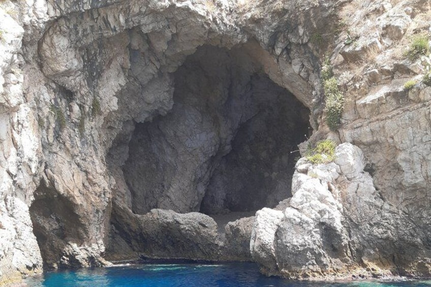 Una formazione rocciosa naturale con un'entrata simile a una grotta e una piscina cristallina ai suoi piedi. 2