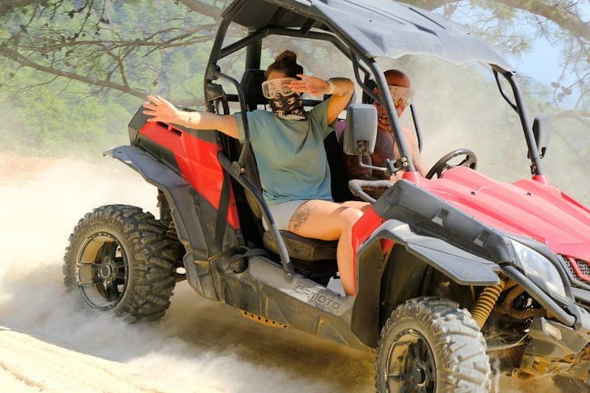 A red ATV with two people, one driving and one sitting, on a dusty trail. 2