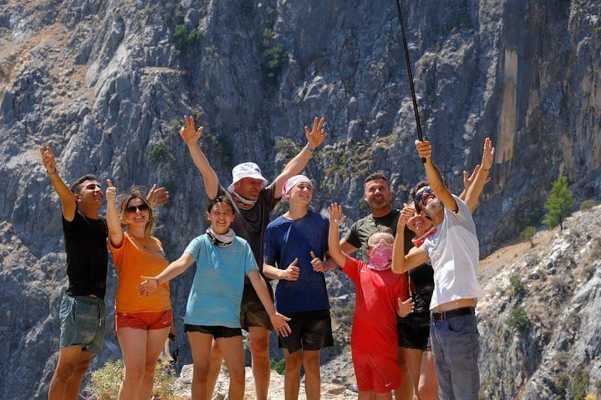 A group of people standing on a mountain ridge with their arms raised, overlooking a rocky landscape. 3