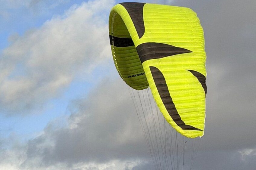 A yellow and black parachute-like object with strings, against a cloudy sky. 3