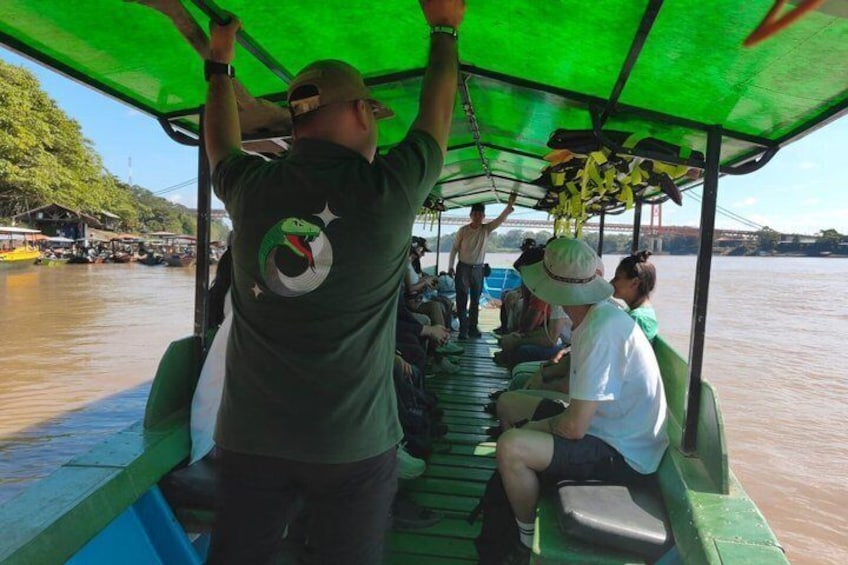 A boat with people on board, a green canopy, and a river. 5