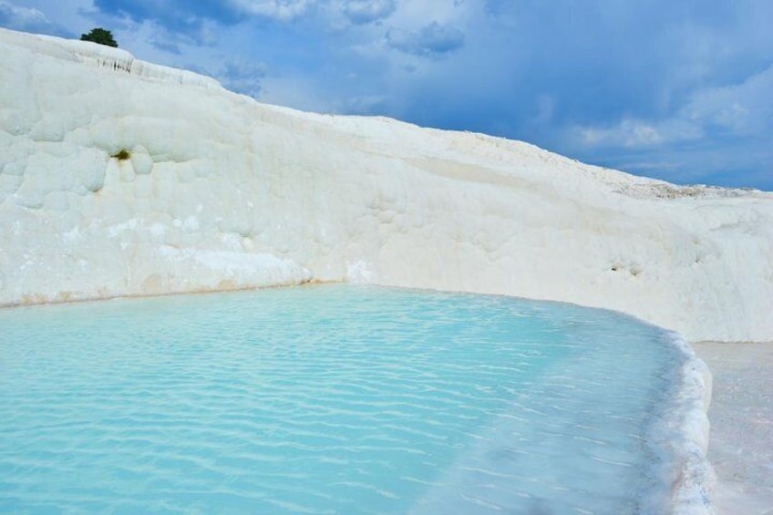 Une piscine turquoise entourée de terrasses blanches en travertin. 4