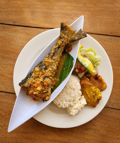 A plate with a whole fish, rice, fried plantains, and a salad. 4