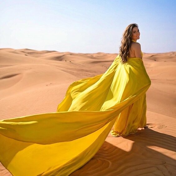 A person in a yellow dress standing on a sand dune. 2