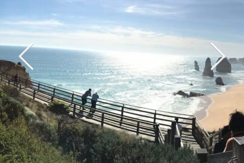 Une promenade en bord de mer où l’on voit des gens se promener, des vagues et des formations rocheuses. 5