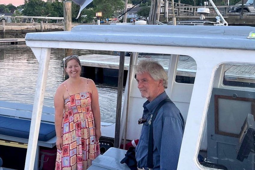A boat docked at a marina with two people standing on the deck. 4